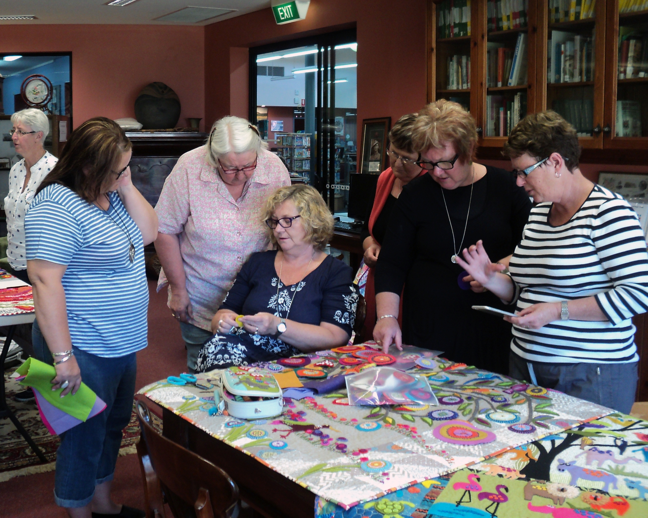 Ladies gathered around a patchwork quilt